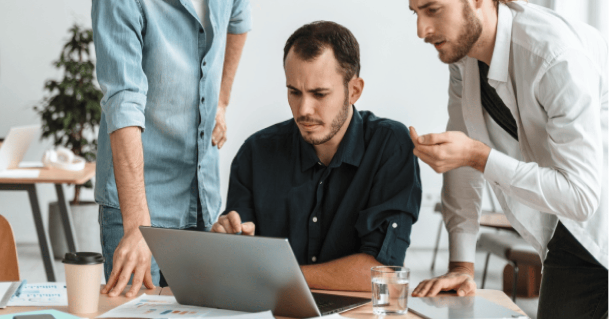 Three colleagues collaborating while looking at a laptop