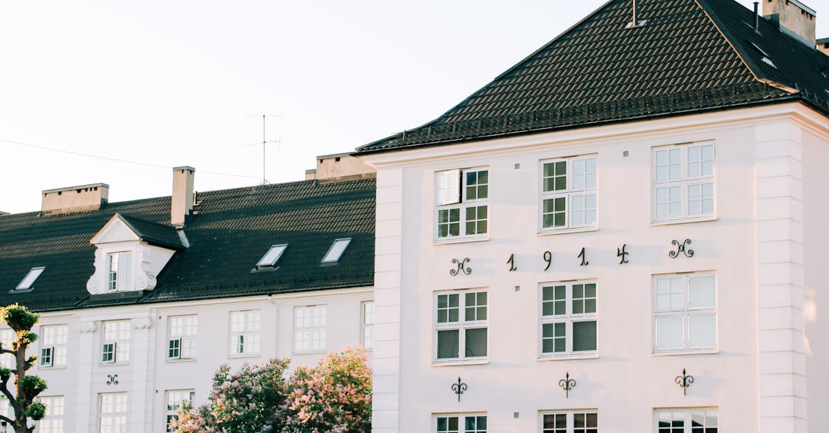 Facade of aged apartment building with white walls located in green area of town