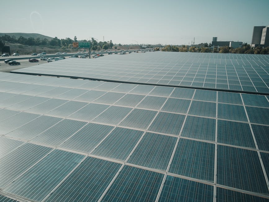 Rows of solar panels near a highway capture renewable energy under a clear sky.