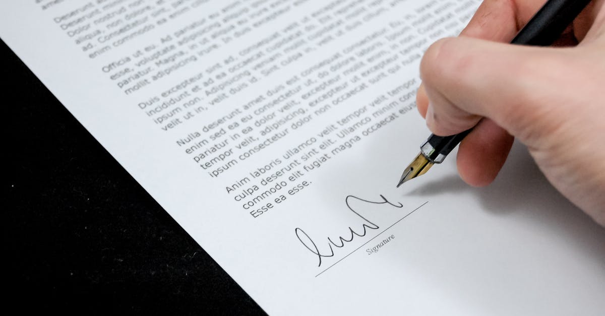 Close-up of a hand signing a formal document with a fountain pen, indicating agreement.