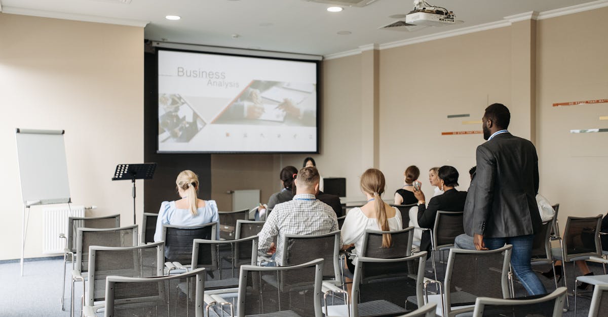Business conference attendees listening to a presentation in an office setting.