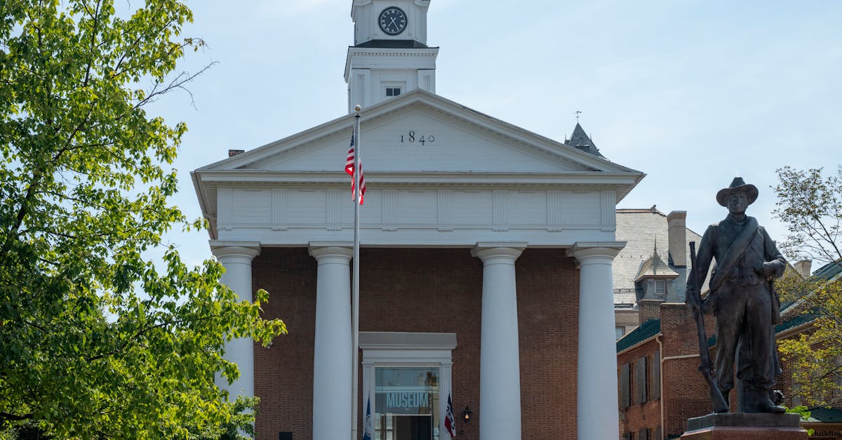 Historic courthouse facade with statue and American flag in daylight.