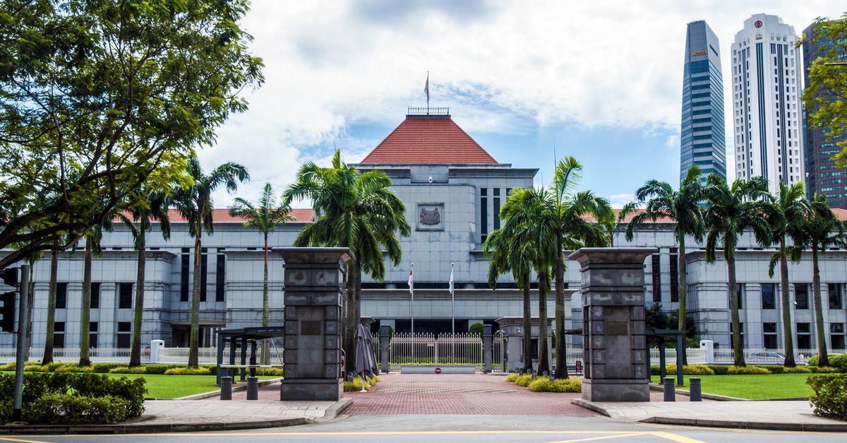 Exterior view of Singapore Parliament House with lush greenery and skyscrapers in the background.