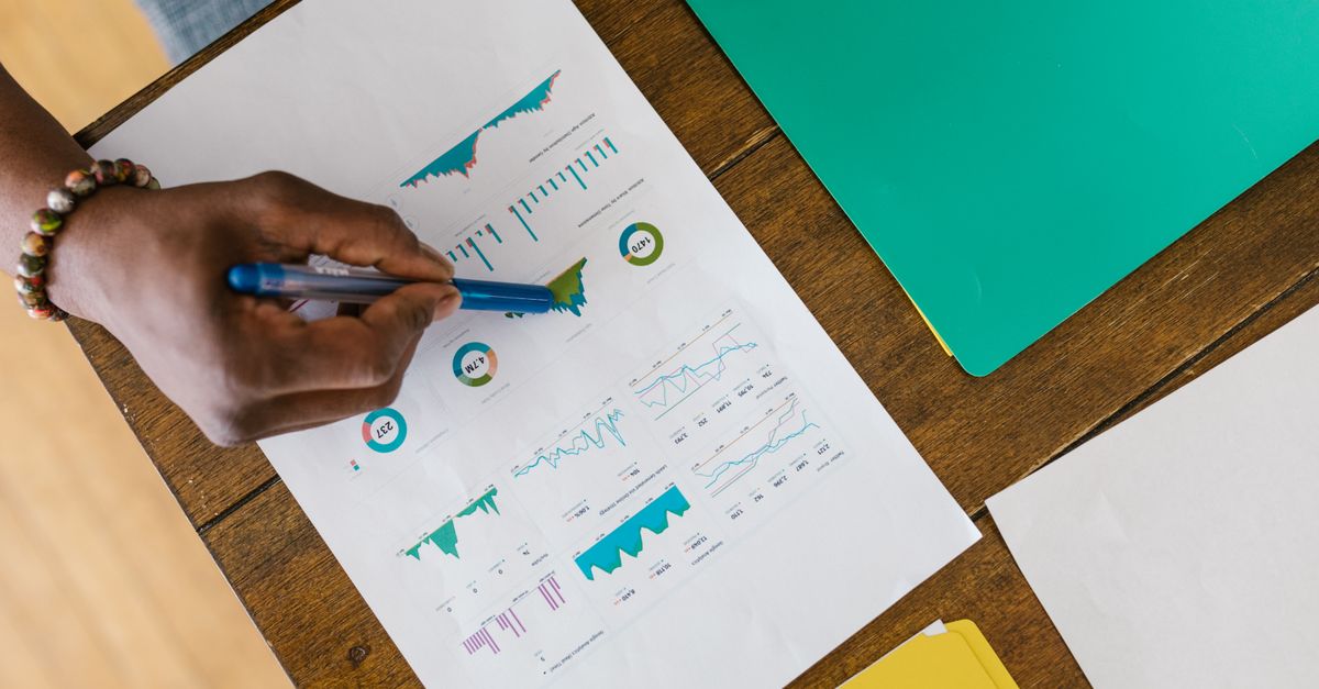 Overhead view of a person analyzing business charts and graphs on paper.