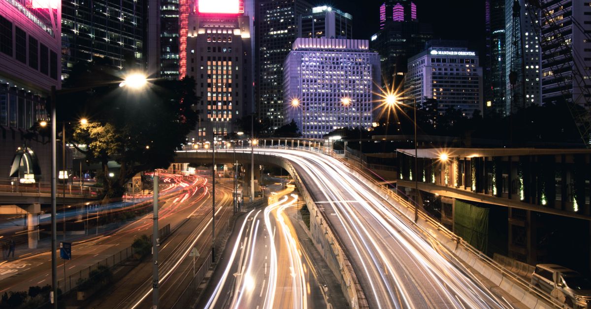 Dynamic night cityscape of Hong Kong with vibrant light trails and skyscrapers.