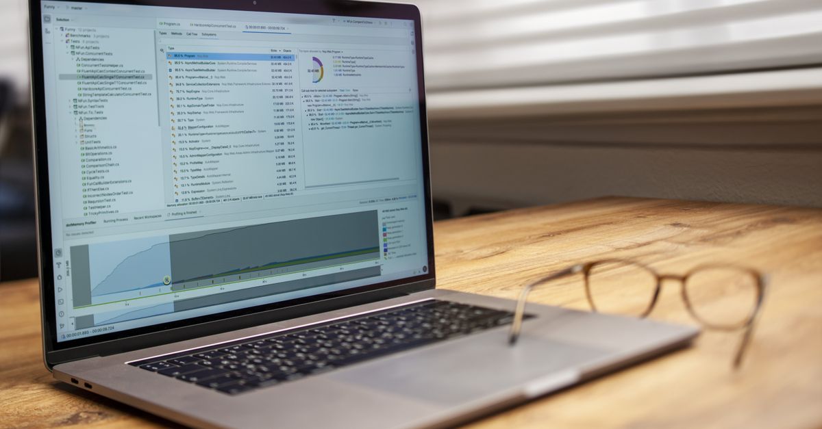Modern laptop on a wooden desk displaying analytical software with eyeglasses nearby, indoor shot.