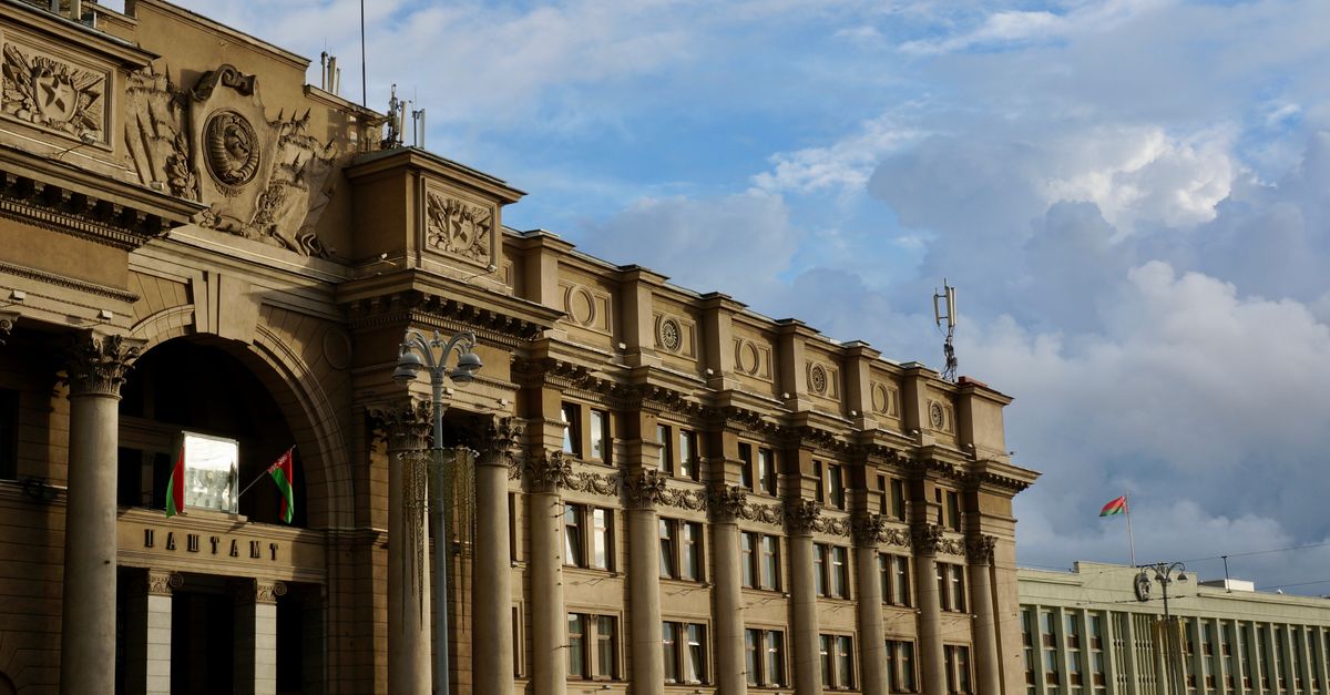 A grand historic building facade with flags and ornate sculptures under a blue sky, ideal for architecture enthusiasts.