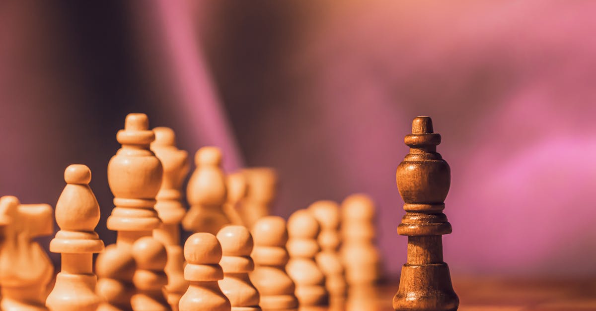 Close-up of wooden chess pieces on a board against a blurred purple backdrop.