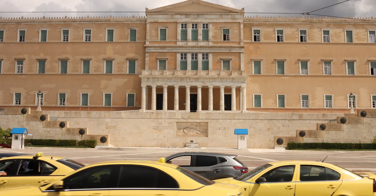 View of the Hellenic Parliament in Athens with yellow taxis in the foreground.