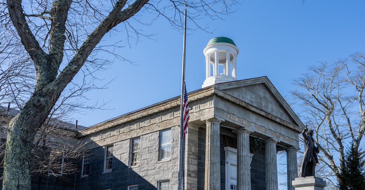 Front view of the historic Barnstable County Courthouse with a prominent statue and flag.