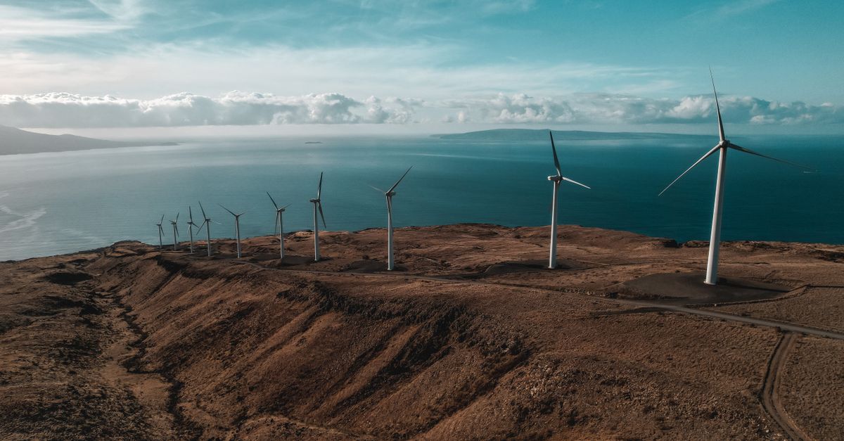Aerial view of a coastal wind farm under a blue sky, symbolizing renewable energy and sustainability.