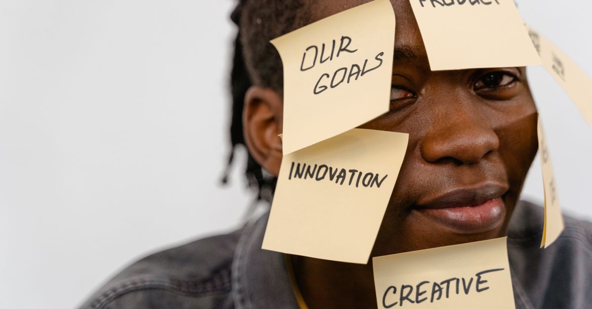 A person with sticky notes on face depicting brainstorming and creative thinking in a studio setting.