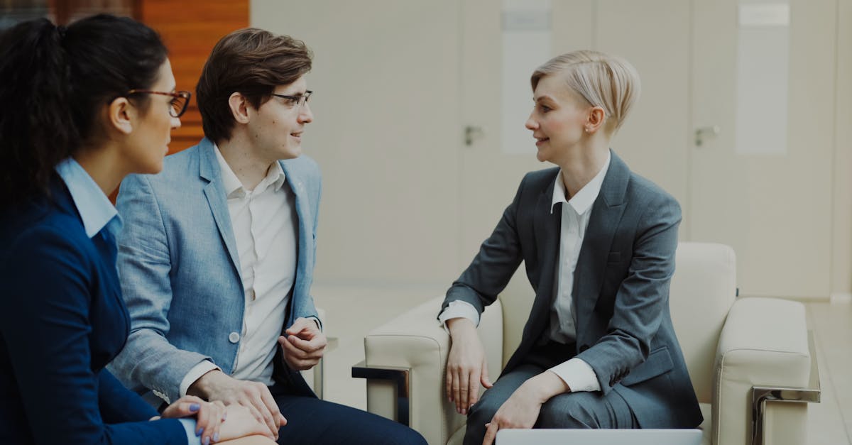Three professionals engaging in a conversation during a business meeting indoors.