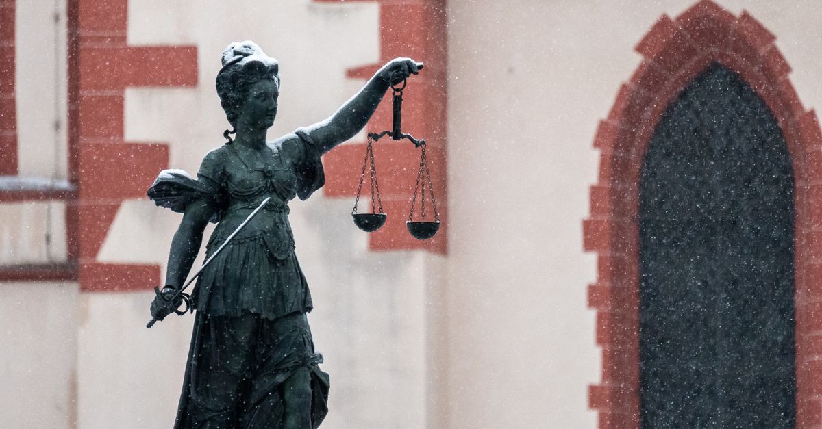A statue of Lady Justice in an urban area during snowfall.