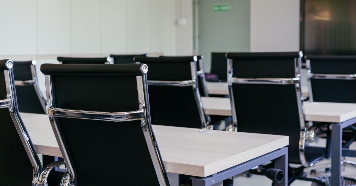 Sleek modern conference room with black chairs and white desks, suitable for business meetings.