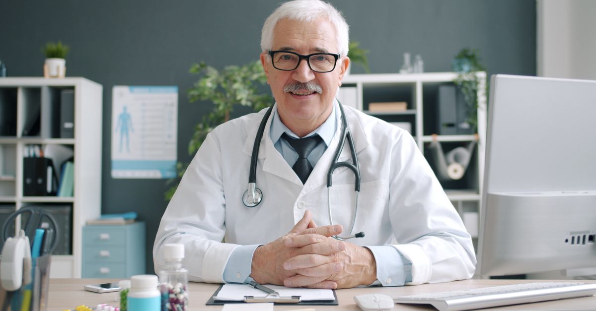 Senior male doctor smiling in a modern office setting, exuding professionalism.