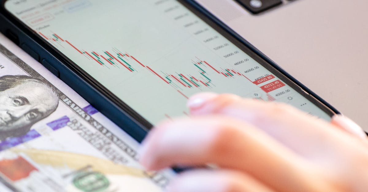 Close-up of a smartphone displaying stock market data over a dollar bill on a desk.