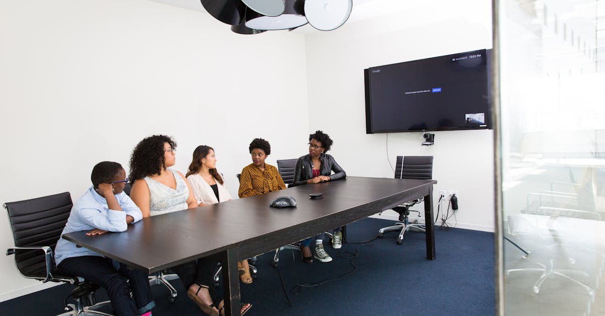 Group of diverse professionals engaged in a meeting in a modern office setting with technology integration.