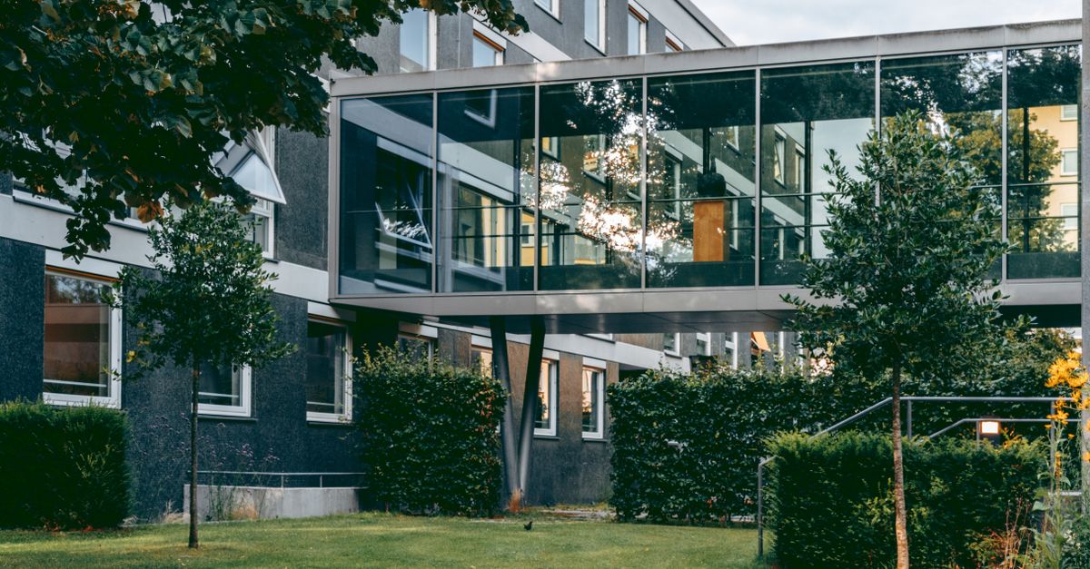 Contemporary architecture with a connecting glass walkway in a lush garden.