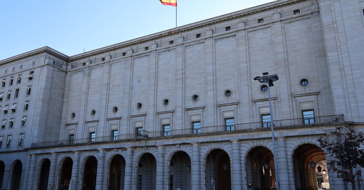 Exterior of a historic government building in Spain with a Spanish flag atop.