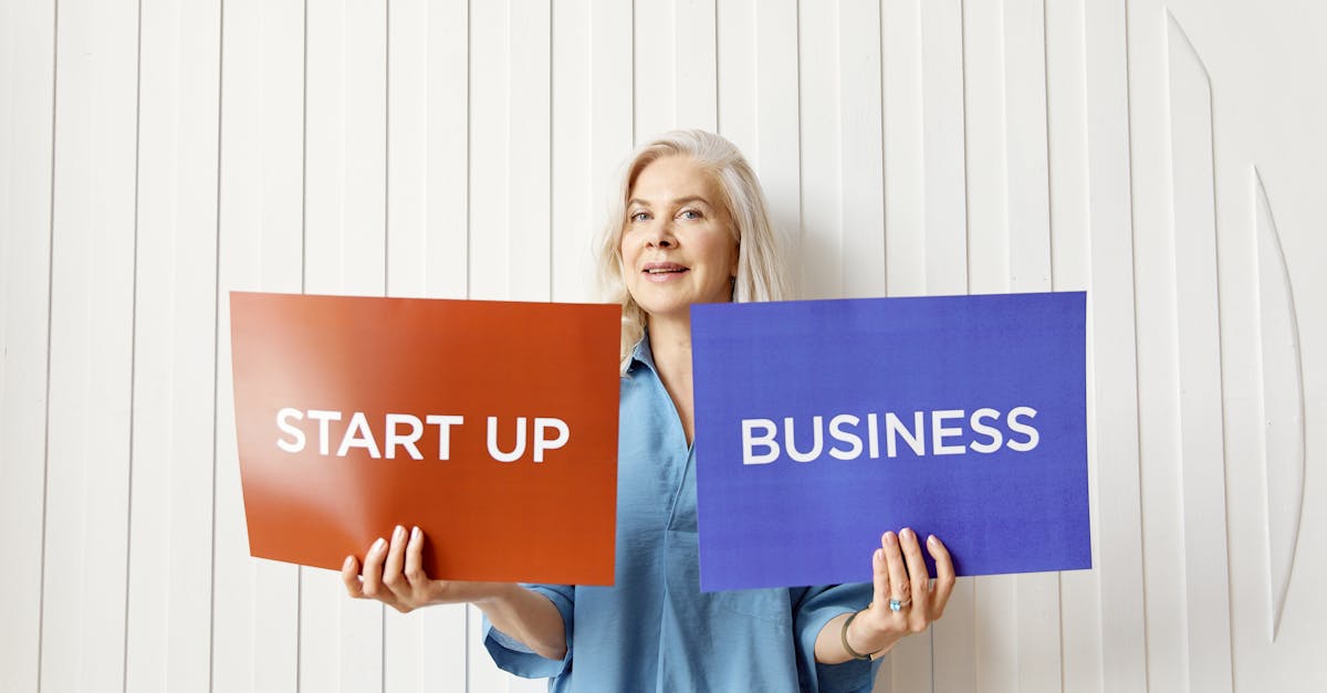 Elderly woman holding startup and business signs indoors against white background.