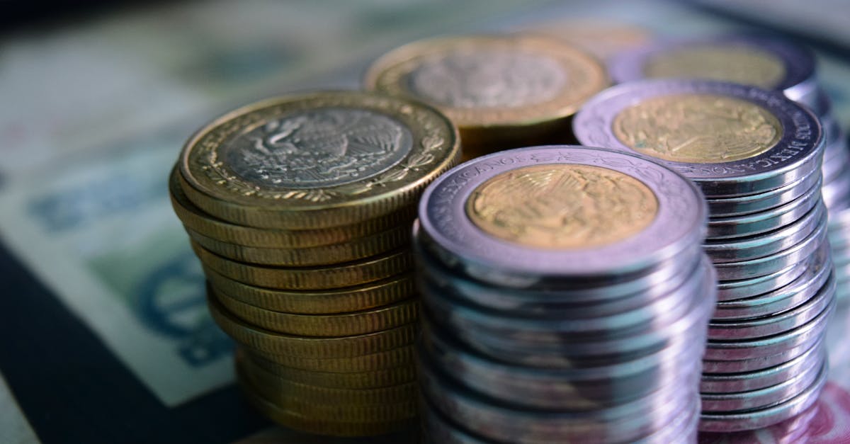 Close-up of stacked gold and silver coins on various currency notes, symbolizing wealth and savings.