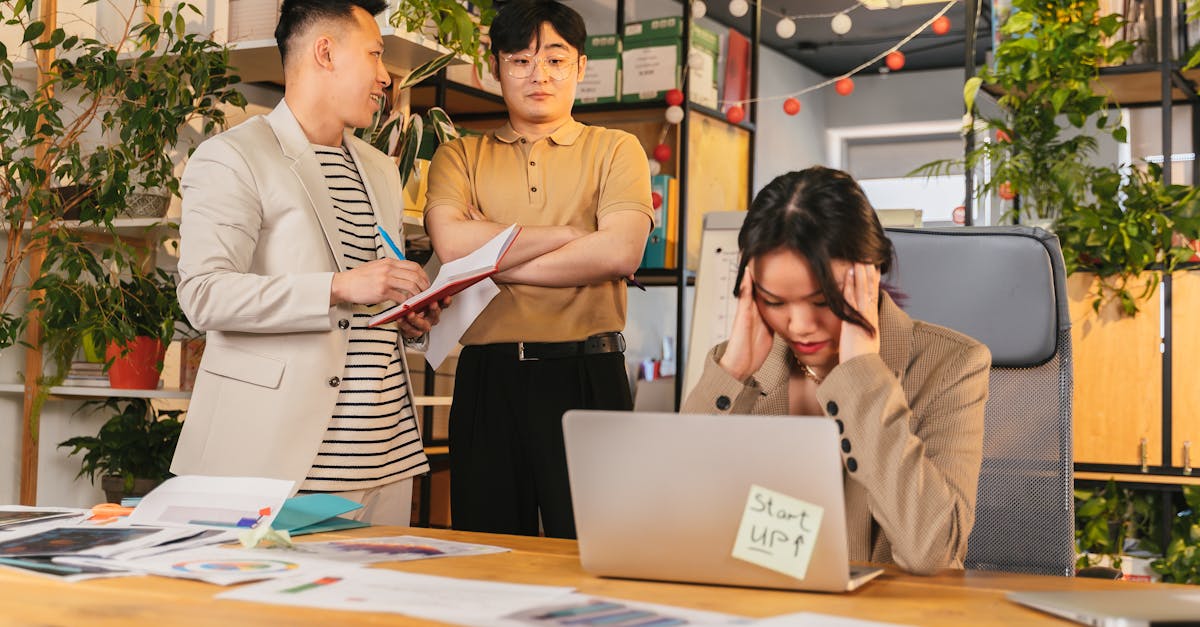 Colleagues engaged in a discussion in a modern office setting with indoor plants and documents.