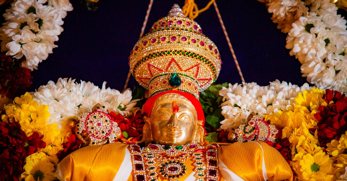 Exquisitely adorned gold statue with gemstones, surrounded by vibrant flowers, symbolizing celebration.