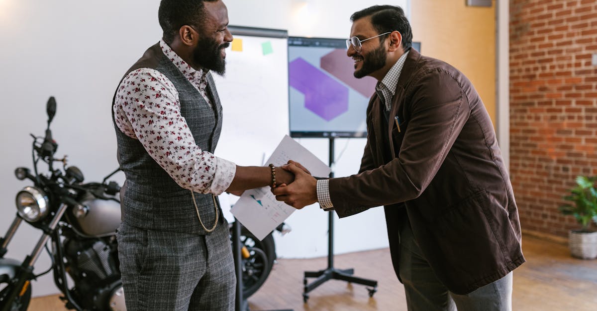 Two male professionals shaking hands in a modern office setting, symbolizing teamwork and collaboration.