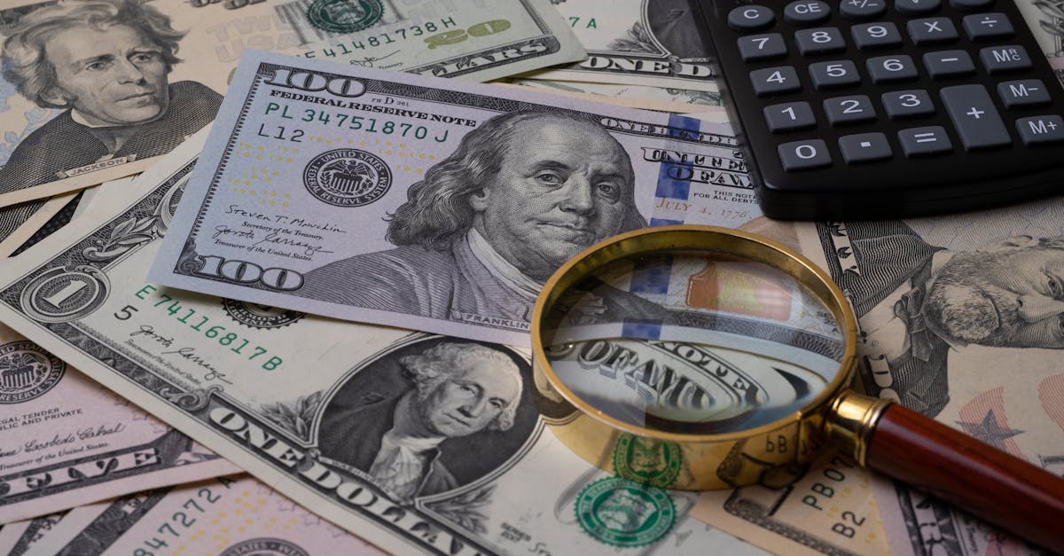 US currency bills with magnifying glass and calculator, symbolizing financial analysis.