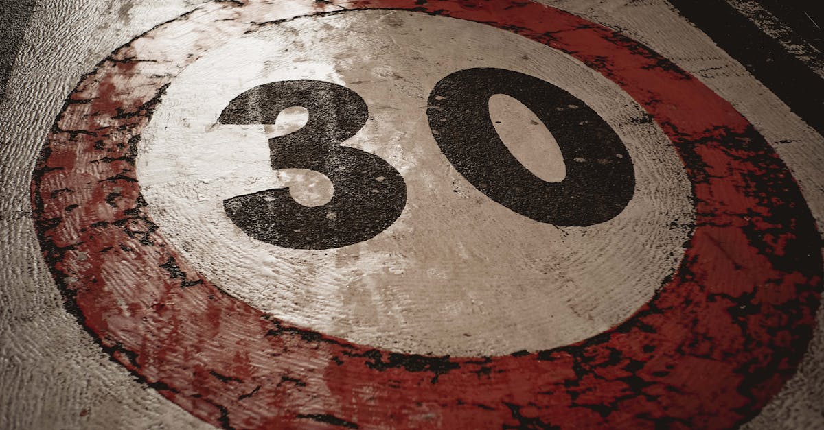 A weathered 30 speed limit sign painted on an asphalt road surface.