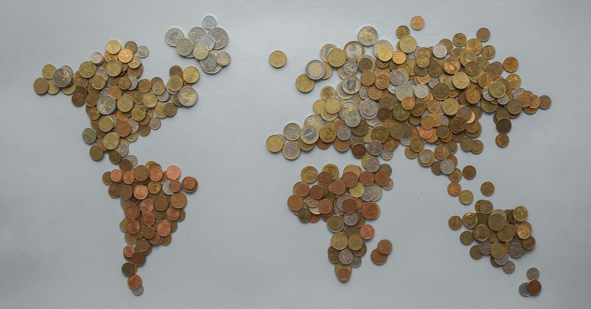 Creative world map made from assorted coins on a solid gray backdrop, symbolizing global finance.