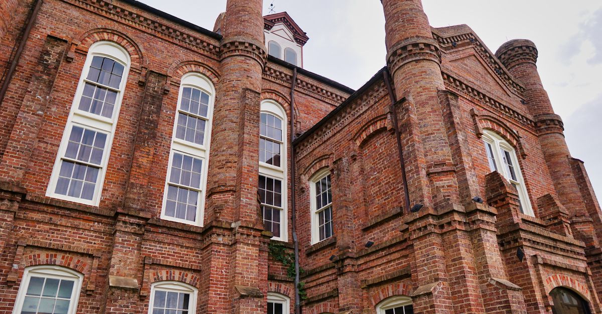 Low-angle shot of a historical brick courthouse featuring arched windows and architectural details.