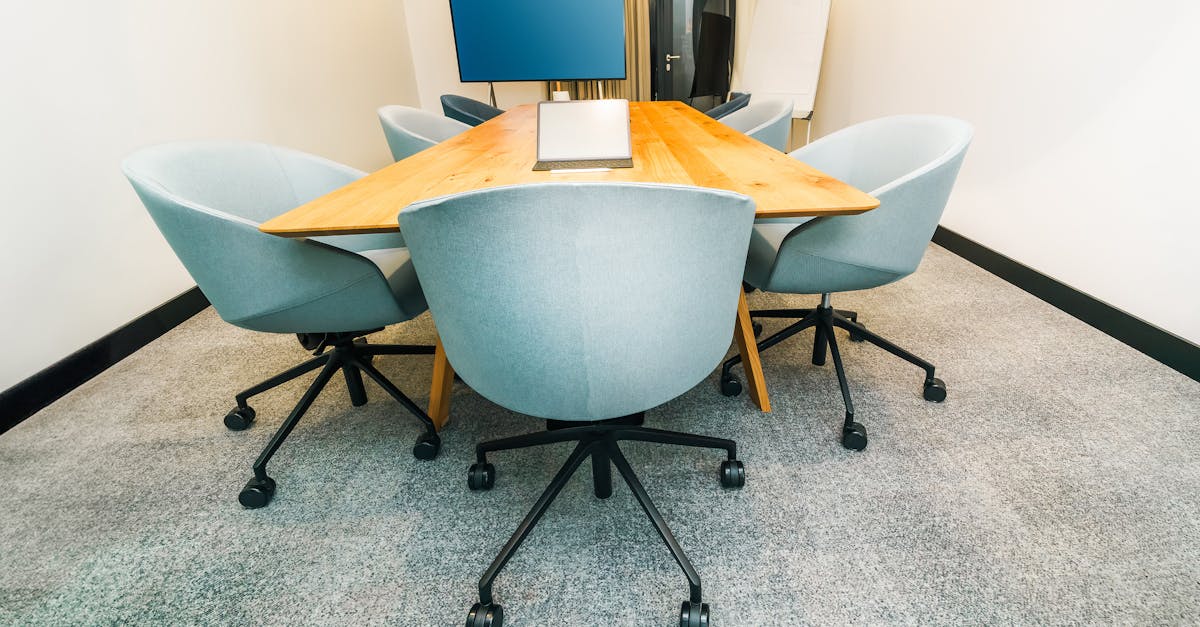 A stylish conference room featuring a triangular table, office chairs, and a TV screen.