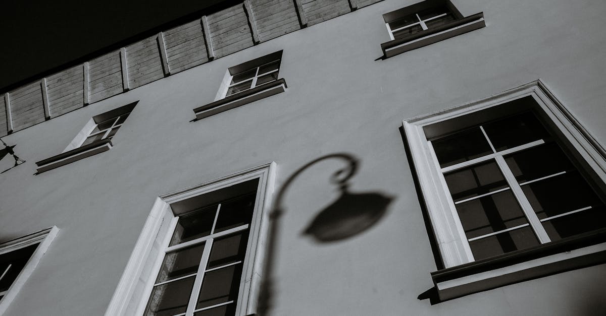 Low-angle grayscale photo of building facade with shadow and window details.