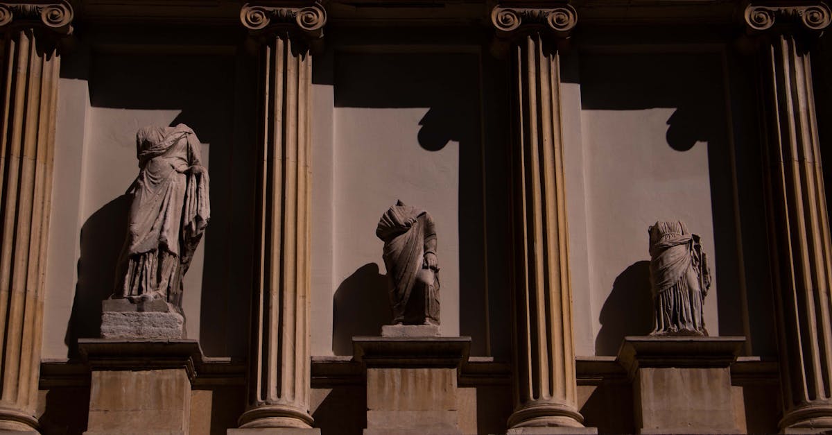 Three headless statues adorn a neoclassical facade in Istanbul, Türkiye, highlighting ancient art.