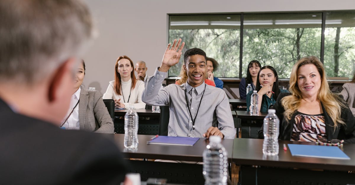 Businesspeople in a conference room engaging in a discussion, with a man raising his hand.