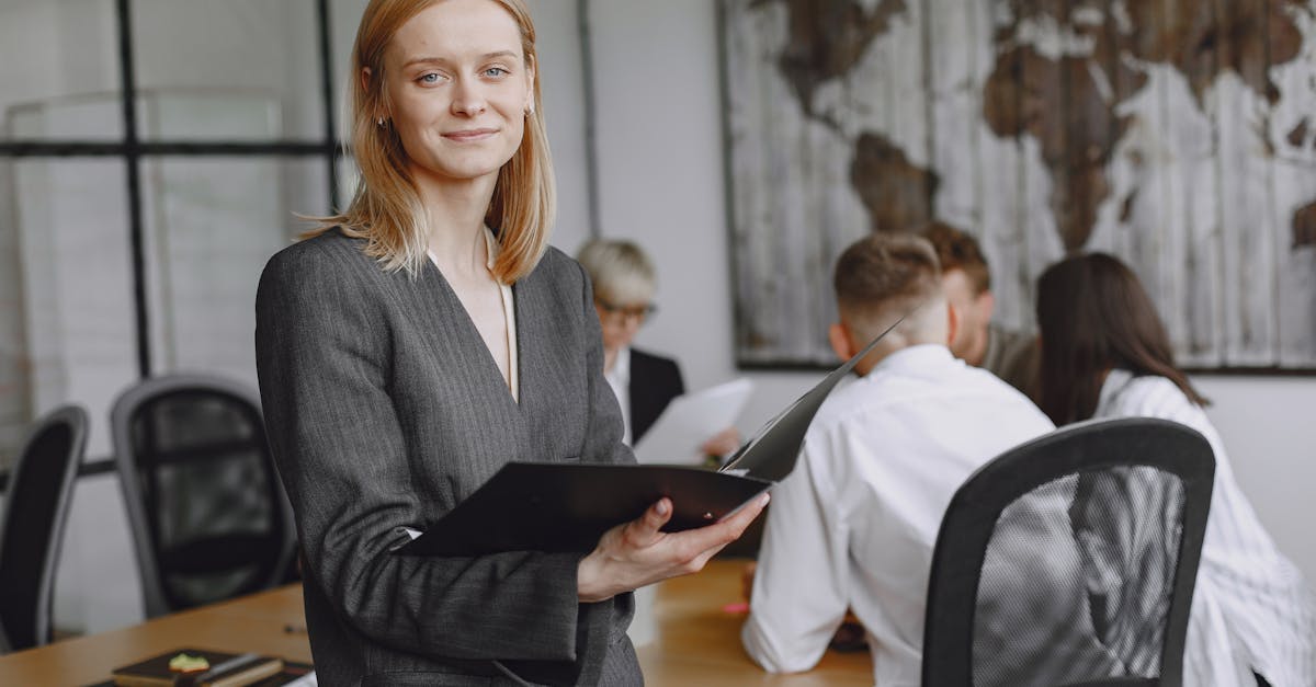 Confident businesswoman holding folder during a team meeting in modern office setting.