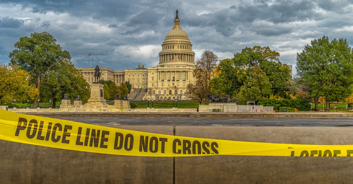 View of US Capitol Building behind police tape under a cloudy sky in Washington, DC.