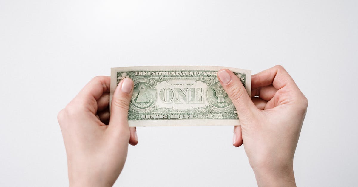 A close-up image of hands holding a one dollar bill, symbolizing finance and economy.