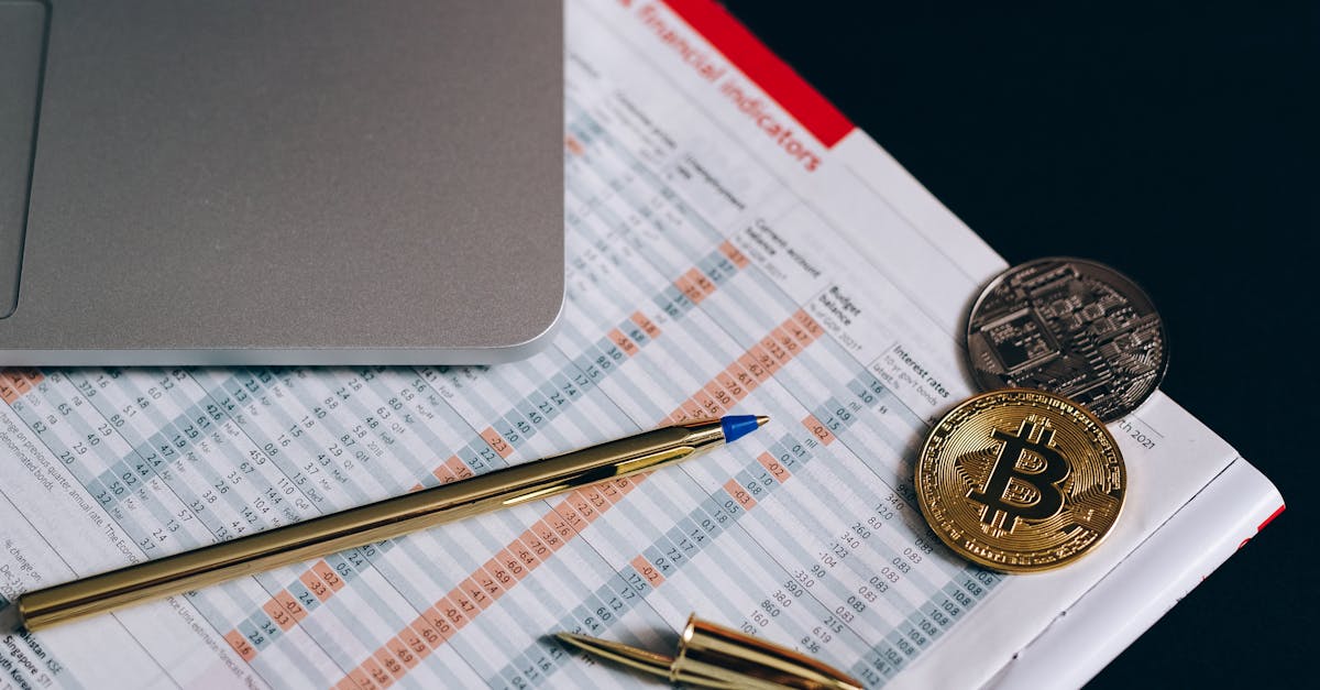 Flat lay of Bitcoin coins on a financial report with a laptop and pen.