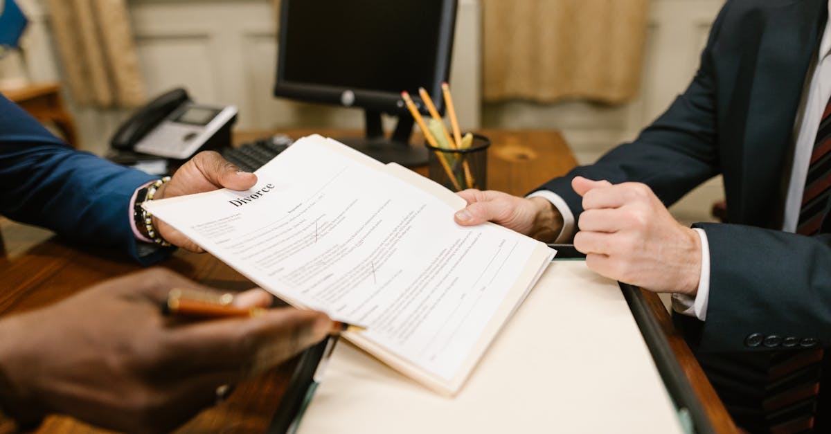 Close-up of hands exchanging divorce documents during legal proceedings in office.