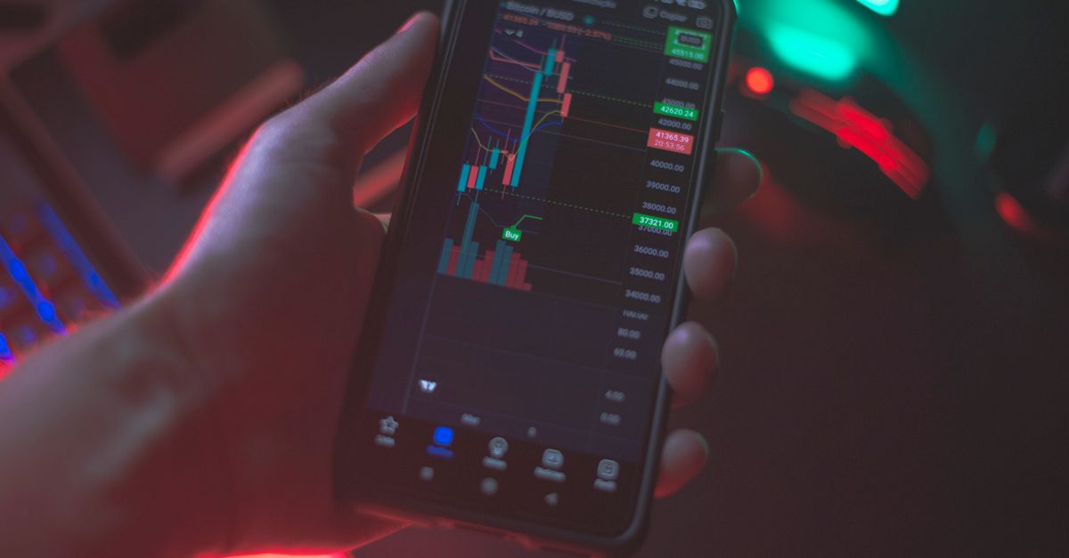 Hand holding smartphone displaying cryptocurrency trading app with financial data.