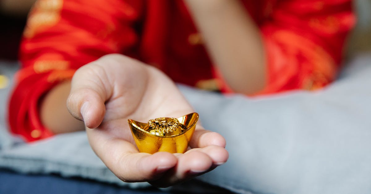 Crop anonymous person in authentic outfit showing Chinese gold bar presented for New Year