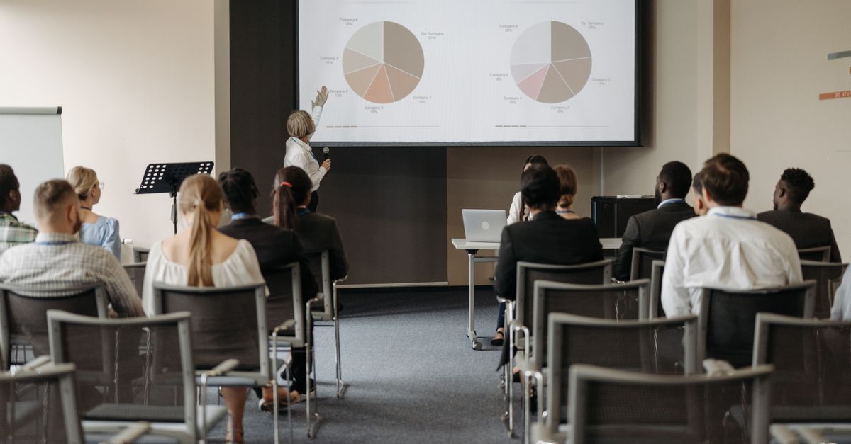 Business conference with diverse audience and speaker presenting market data.