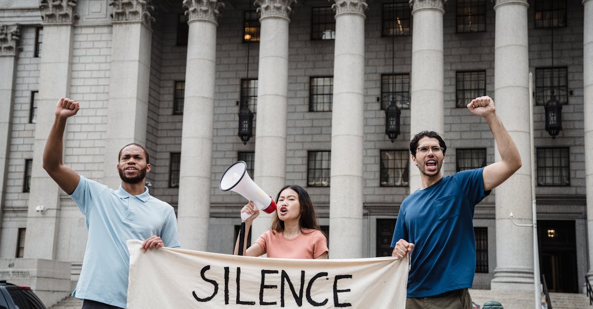 Group of activists raising fists and chanting with a protest banner outside a government building.