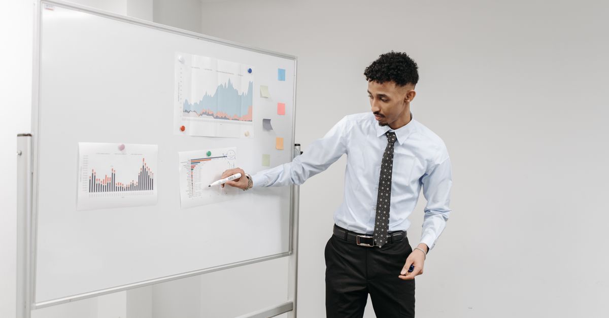 Man presenting charts on a whiteboard during a business meeting in a contemporary office.