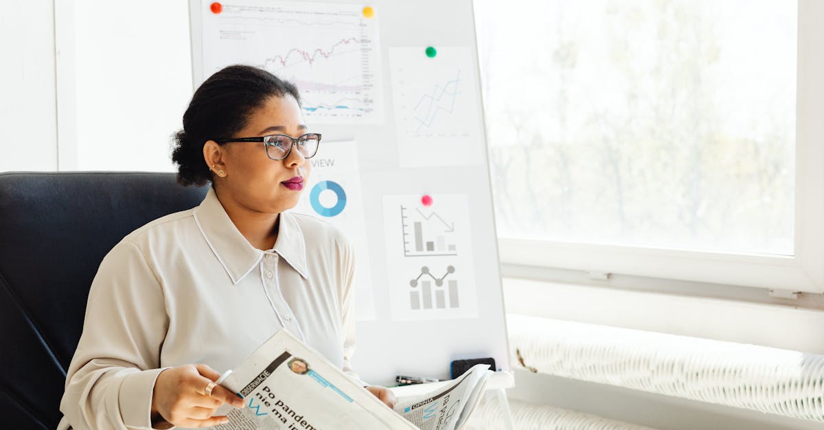 Confident businesswoman reading newspaper and analyzing market trends in a modern office setting.