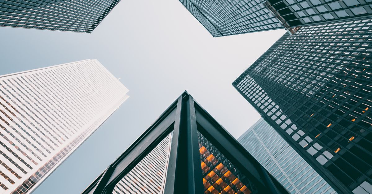 Low angle view of modern skyscrapers with glass facades against a clear sky.