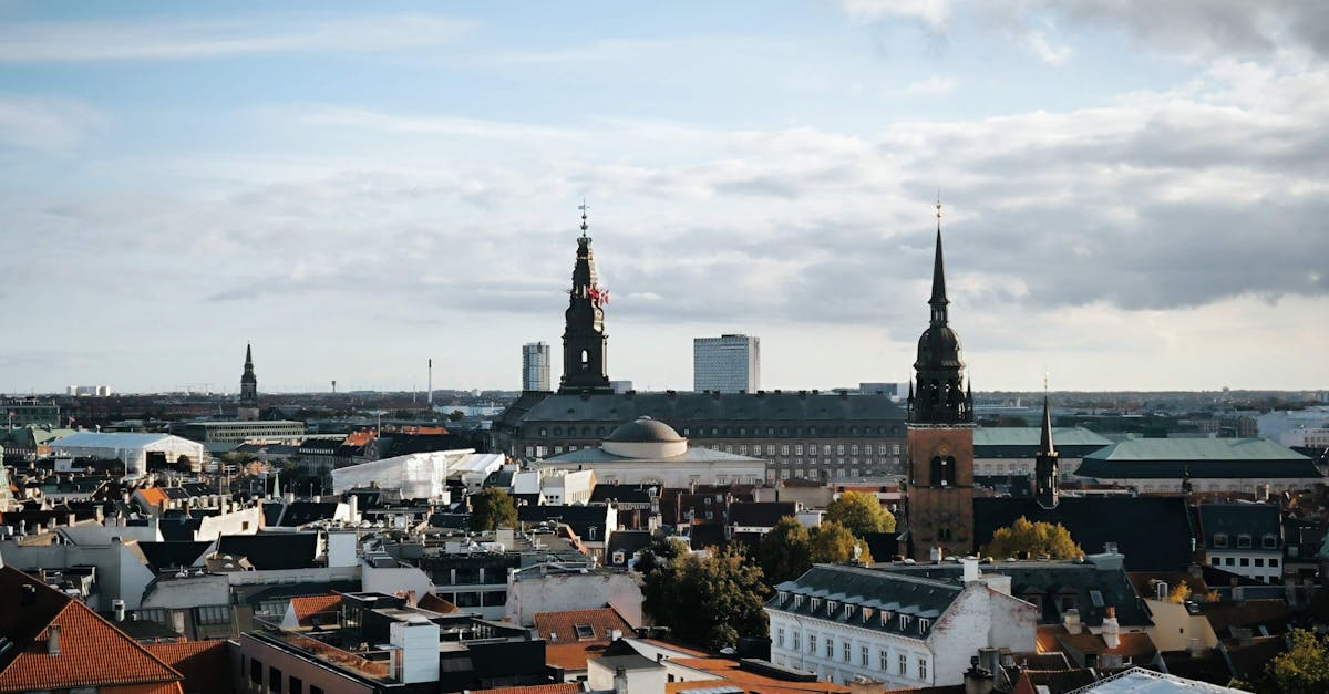 A stunning aerial view of Copenhagen's historic cityscape featuring prominent architectural landmarks under a blue sky.